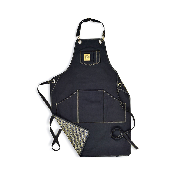 Les tabliers de tatouage Black N Gold Legacy - Tissu présentent un design noir avec des surpiqûres beige, plusieurs poches sur le devant, des bretelles réglables au niveau du cou et de la taille, et une doublure intérieure à motifs, le tout sur fond blanc