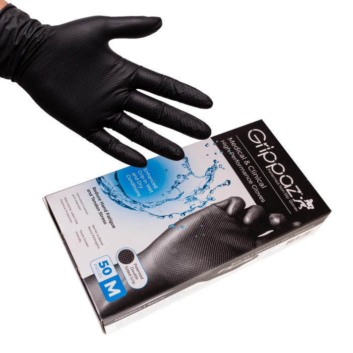 Une main portant un gant en nitrile texturé noir est représentée au-dessus d'une boîte étiquetée "Boite de 50 gants Grippaz - Gants antidrapants haute performance en nitrile - Noirs", qui contient 50 gants noirs antidérapants haute performance de taille m Une main portant un gant en nitrile texturé noir est représentée au-dessus d'une boîte étiquetée "Boite de 50 gants Grippaz - Gants antidrapants haute performance en nitrile - Noirs", qui contient 50 gants noirs antidérapants haute performance de taille m