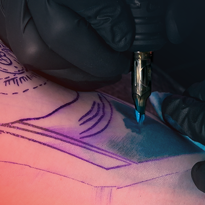 Un primer plano de una persona recibiendo sombreado azul en su tatuaje.